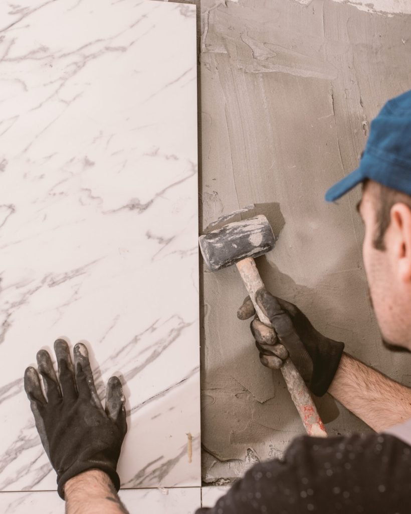 Handyman instaling ceramic tiles on the bathroom wall